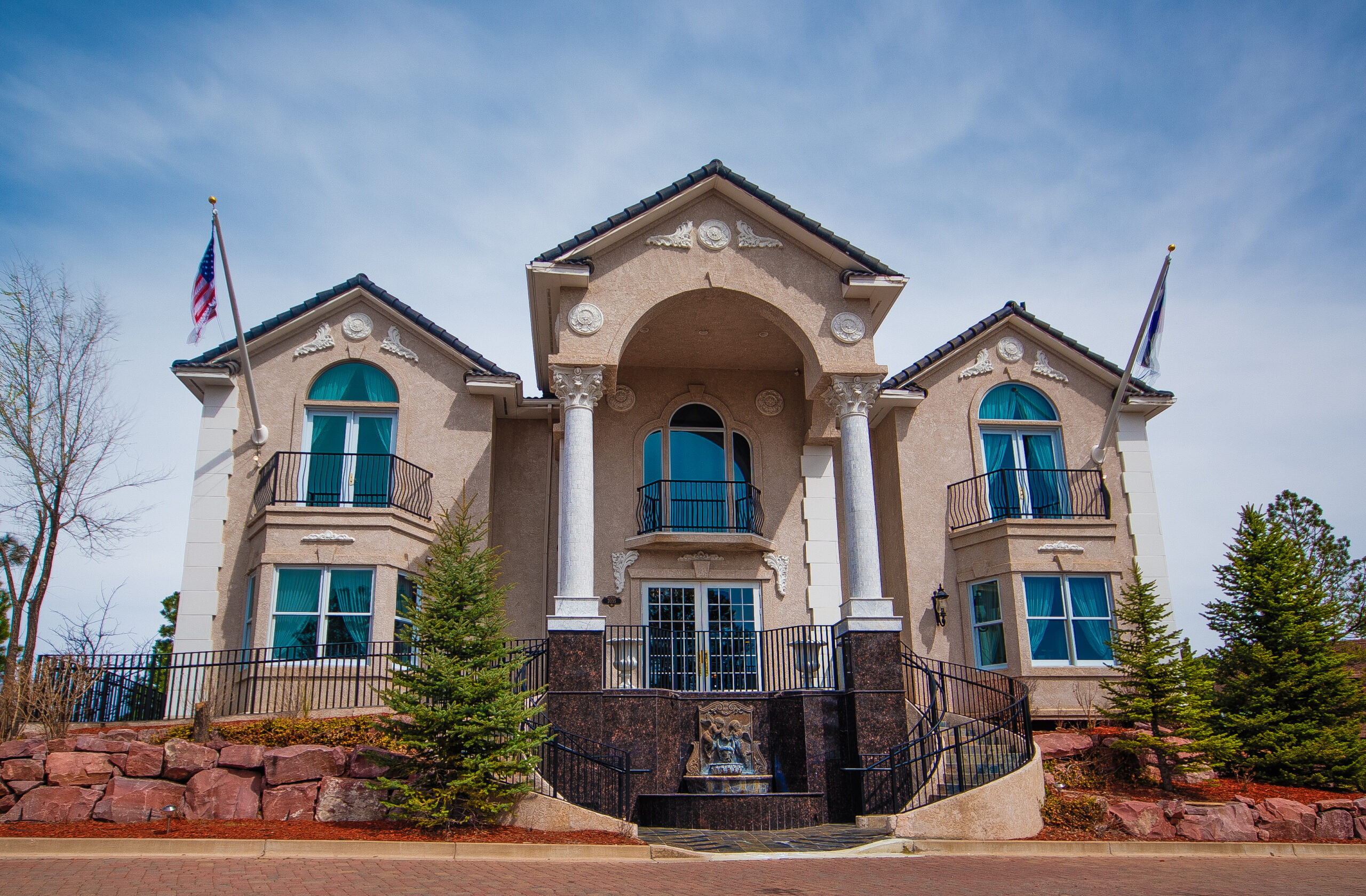 Front entrance of 7035 Campus Drive with a columned portico, arched windows and flags