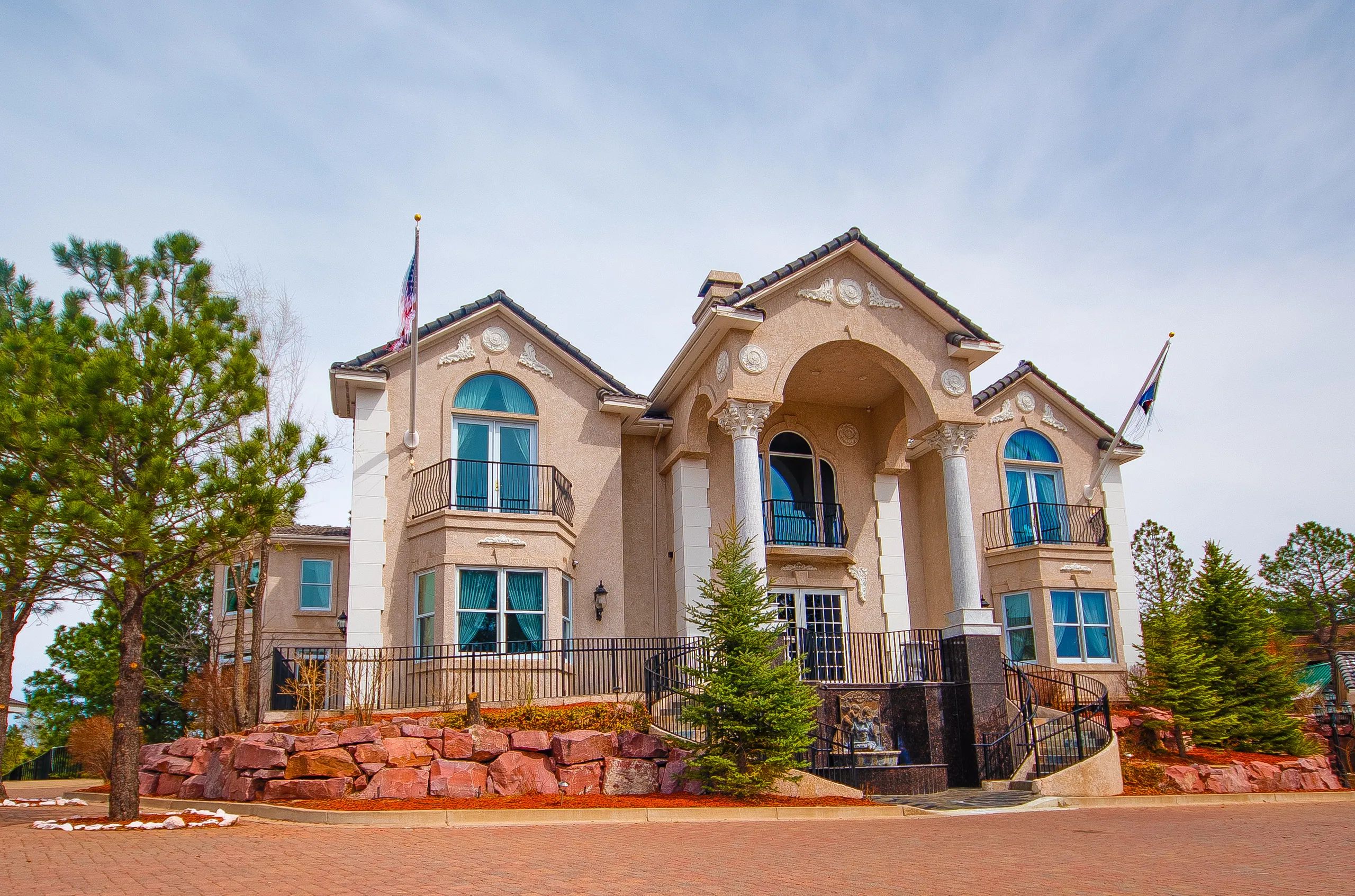7035 Campus Drive: stucco office building with arched windows, columned entry and flags among pine trees